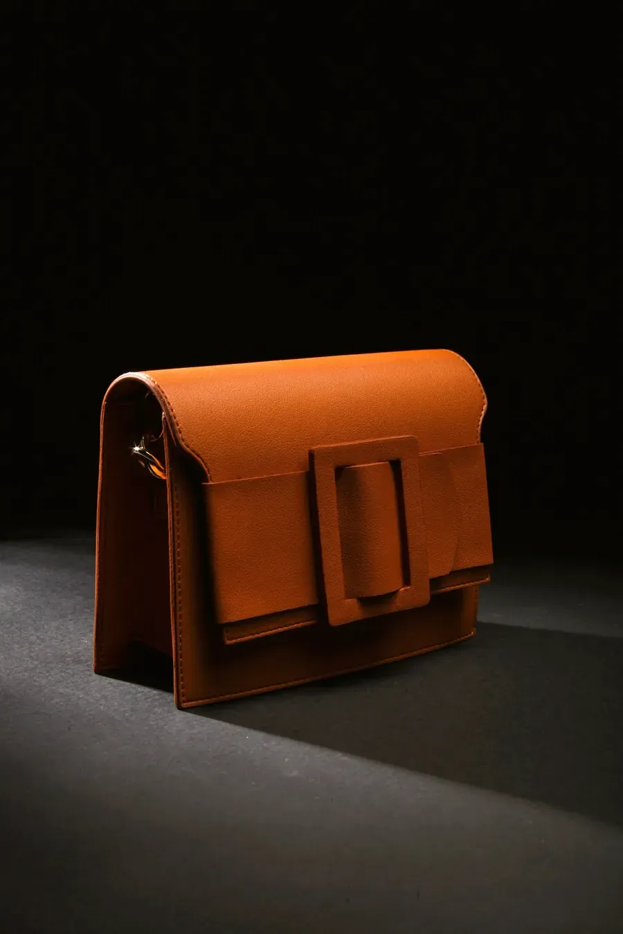 Brown leather shoulder bag on a dark surface