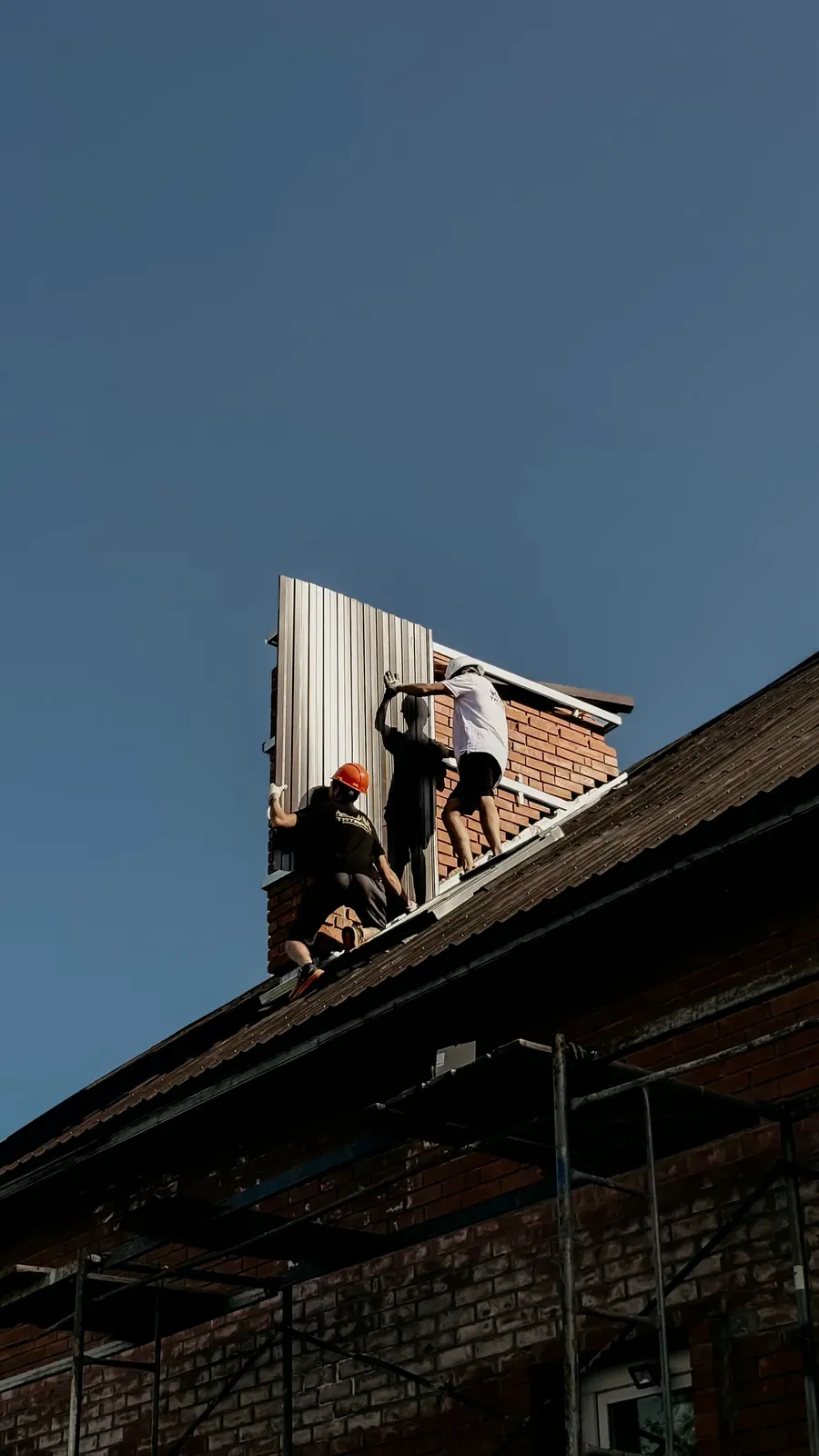 Workers installing metal roof panels